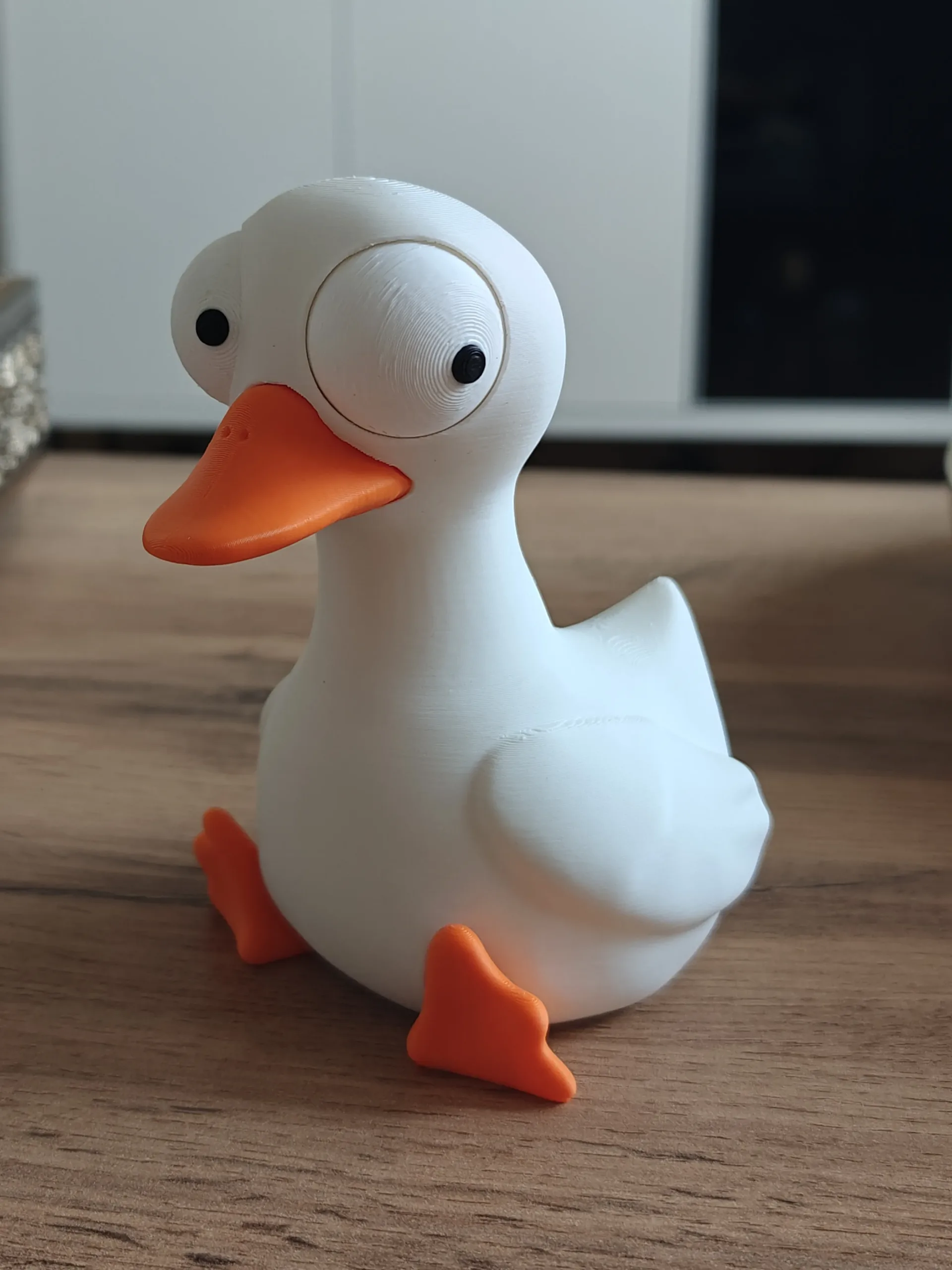 3D nyomtatott kacsa figura, cartoon / kawaii / quirky, dülledt szemű (bug-eyed), matt fehér test, narancs csőr és lábak – 3D nyomtatott dülledt szemű kacsa figura, oldalnézet, profil